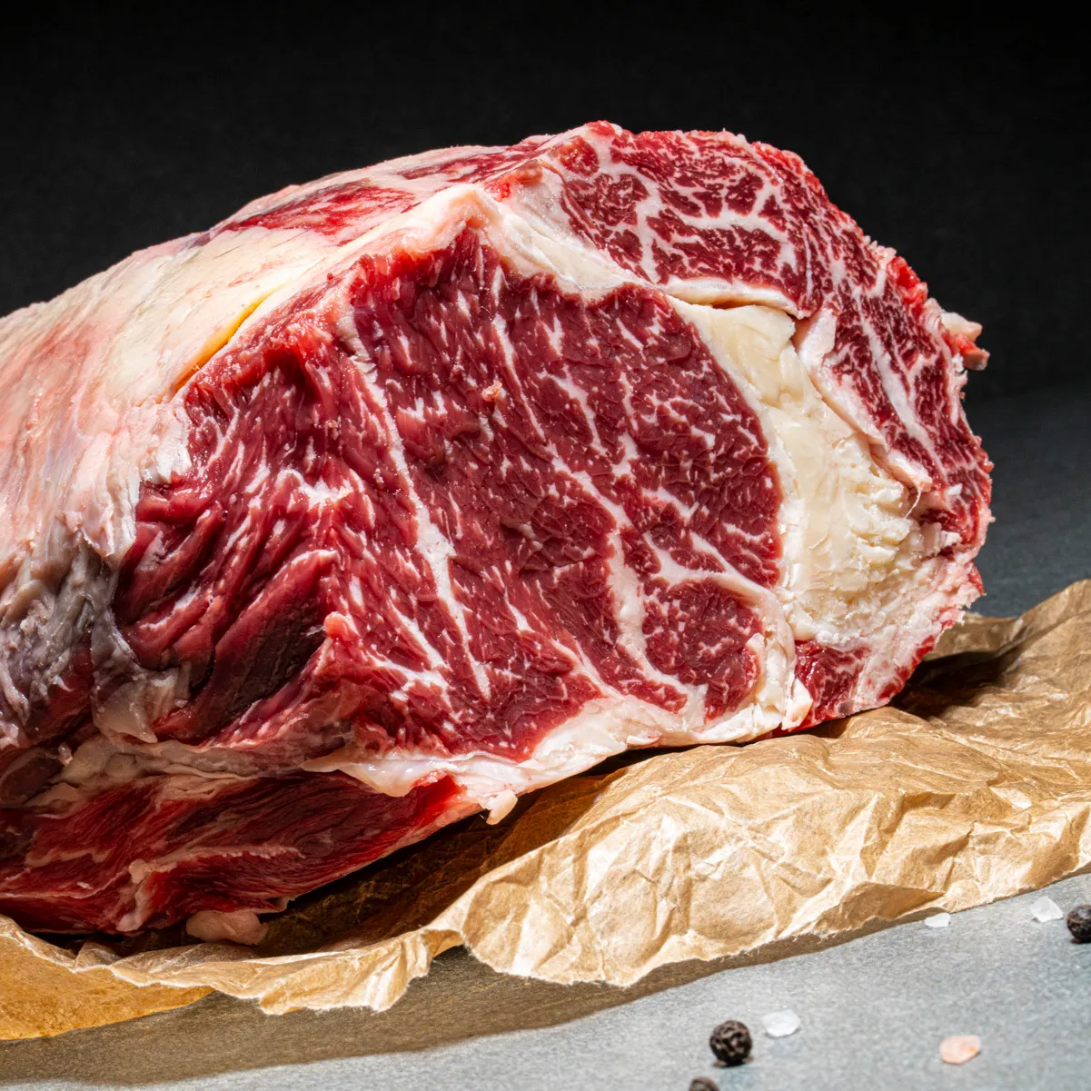Ribeye Steak vom Angus Rind im Anschnitt auf Fleischpapier, das Fettauge ist gut zu sehen sowie die Fleischmaserung.