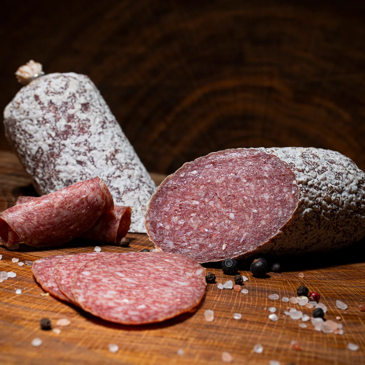 Probieren Sie unsere Mangalitzasalami in klein! Mangalitzasalami in klein, aufgeschnitten auf einem Holzbrett.