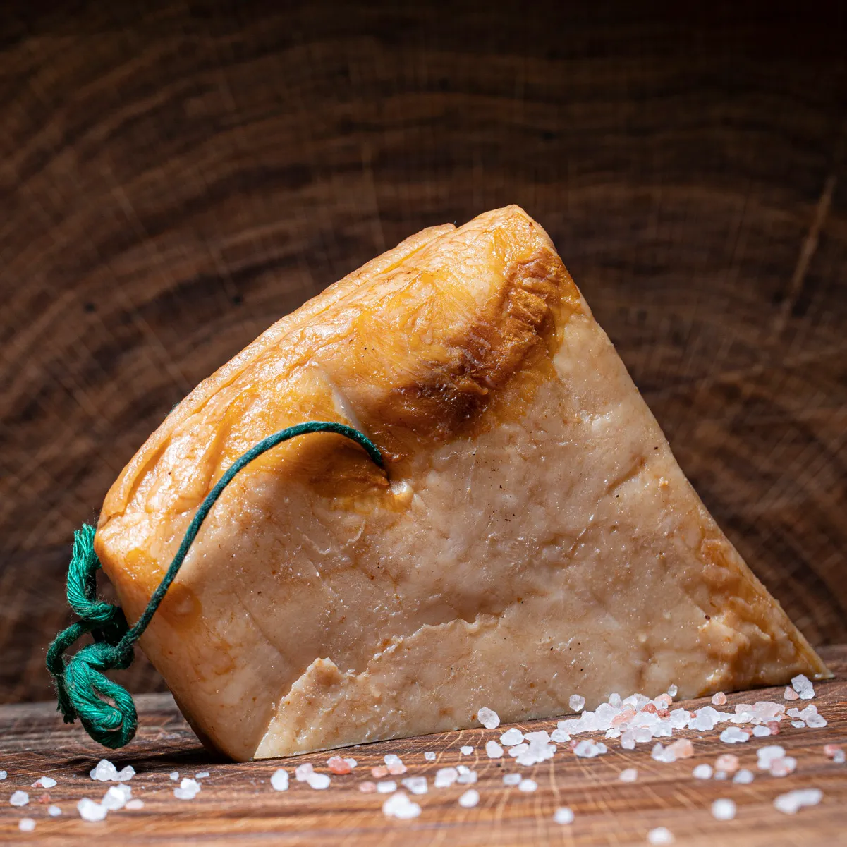 Geräucherter dicker Speck jetzt bestellen. Geräucherter dicker Speck halbiert mit Salz Deko auf Holzbrett.