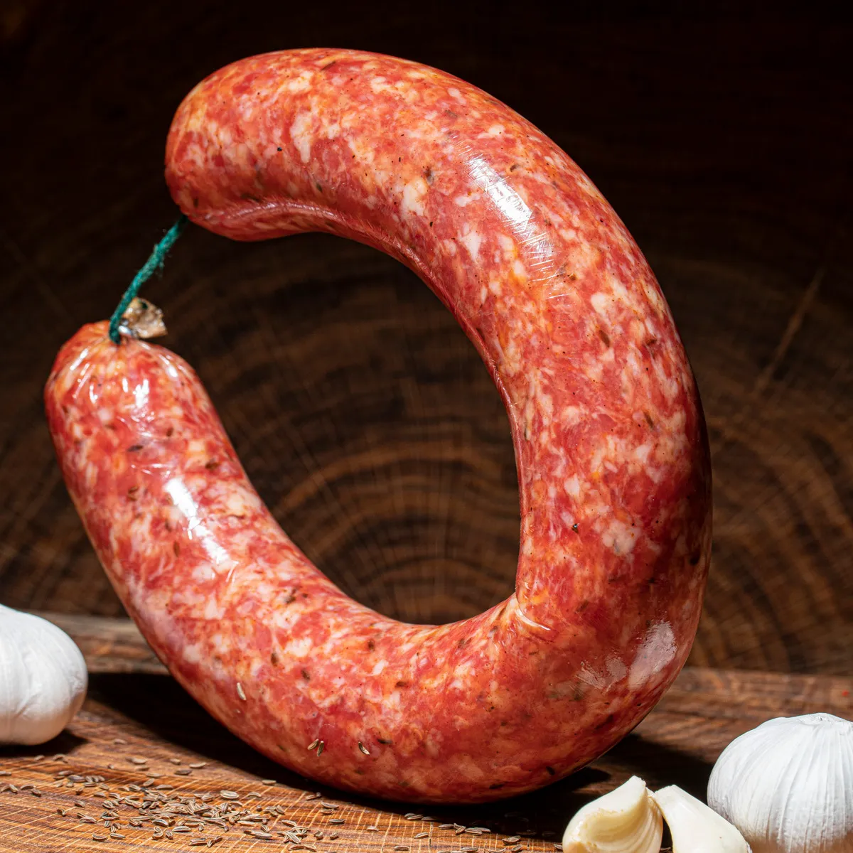 Unsere würzige Schinkenpolnische jetzt bestellen! Schinkenpolnische ganzer Ring auf Holztisch.