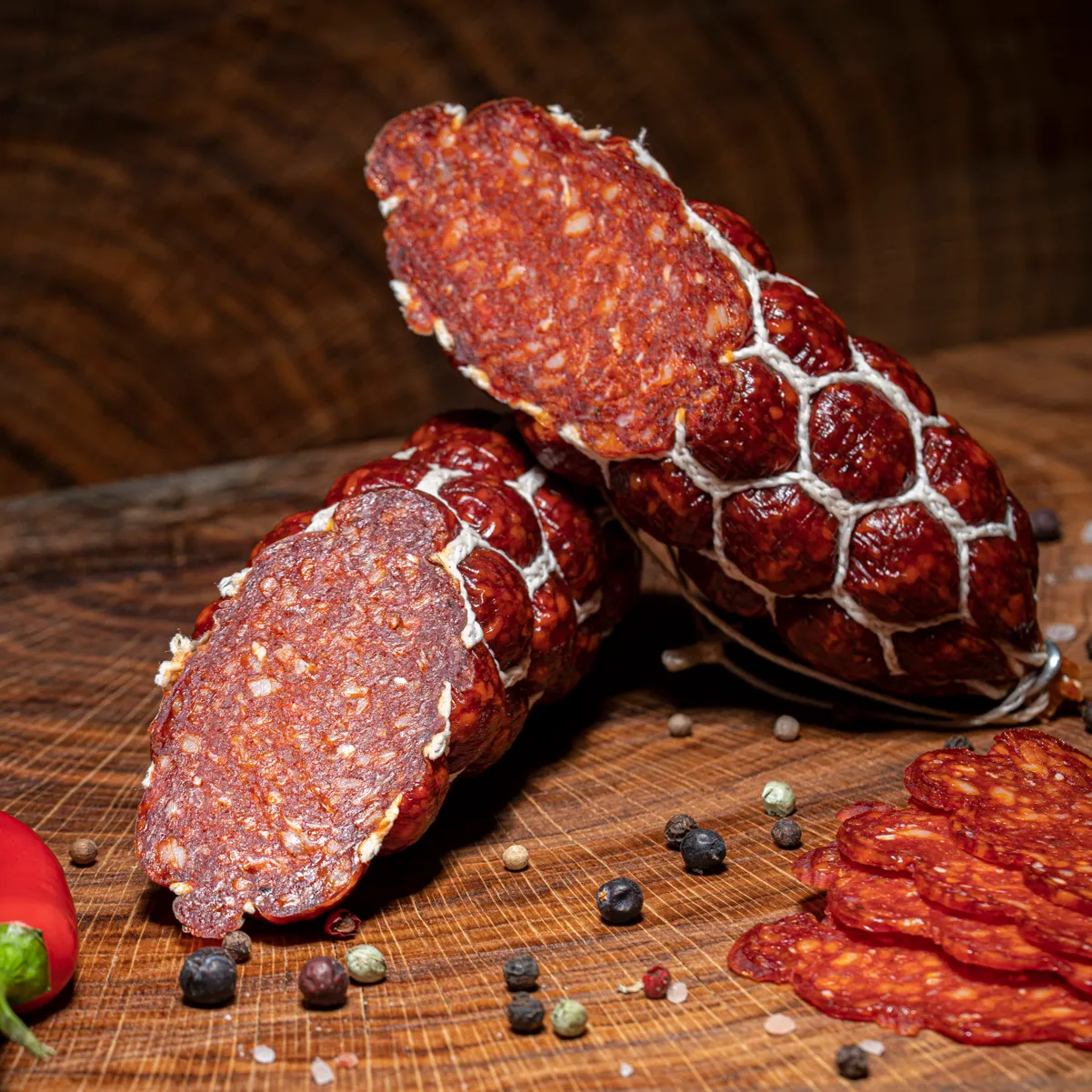 Jetzt unsere scharfe Teufelssalami in klein bestellen! Kleine Teufelssalami aufgeschnitten auf Tischplatte.