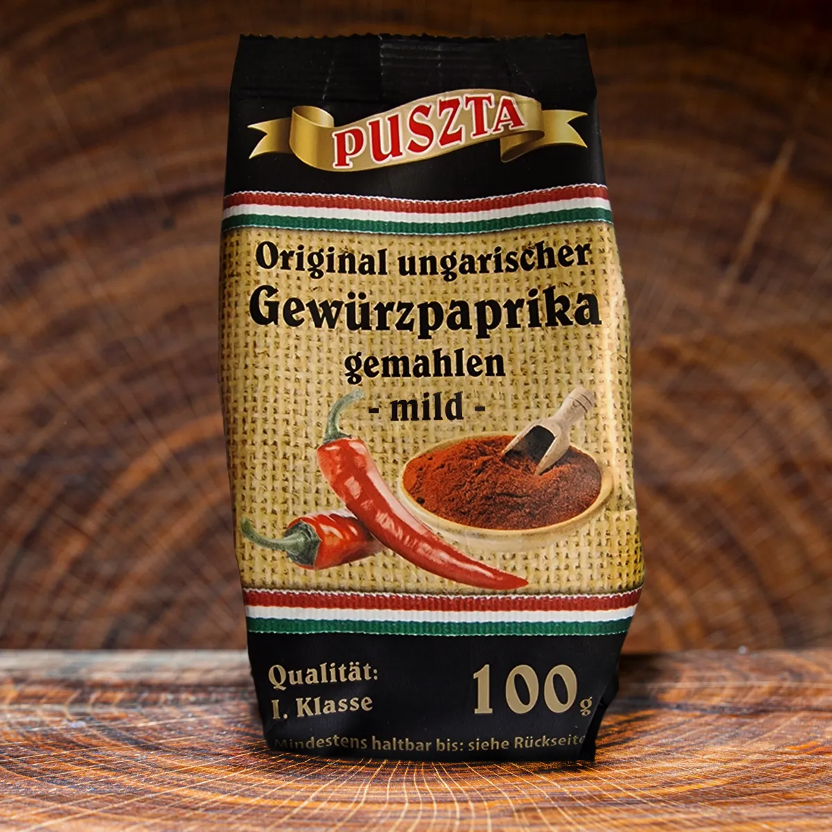 Puszta ungarischer Gewuerzpaprika mild bestellen. Puszta ungarischer Gewuerzpaprika Pulver mild auf einem Holzbrett.