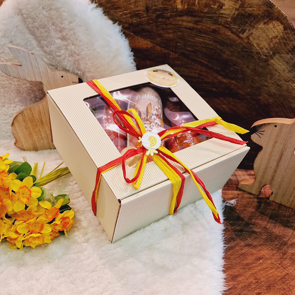 Osterpräsent verpackt mit Schleife und Wurstwaren wie Rollschinken und Höllenwurst als Inhalt.