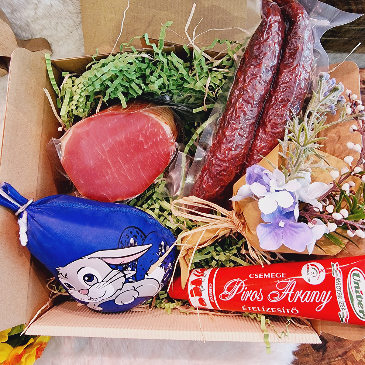 Hoppelnde Osterfreude Geschenkbox online bestellen! Osterpräsentbox in Szene gesetzt mit Rollschinken, Gulaschcreme und Motivsalami.