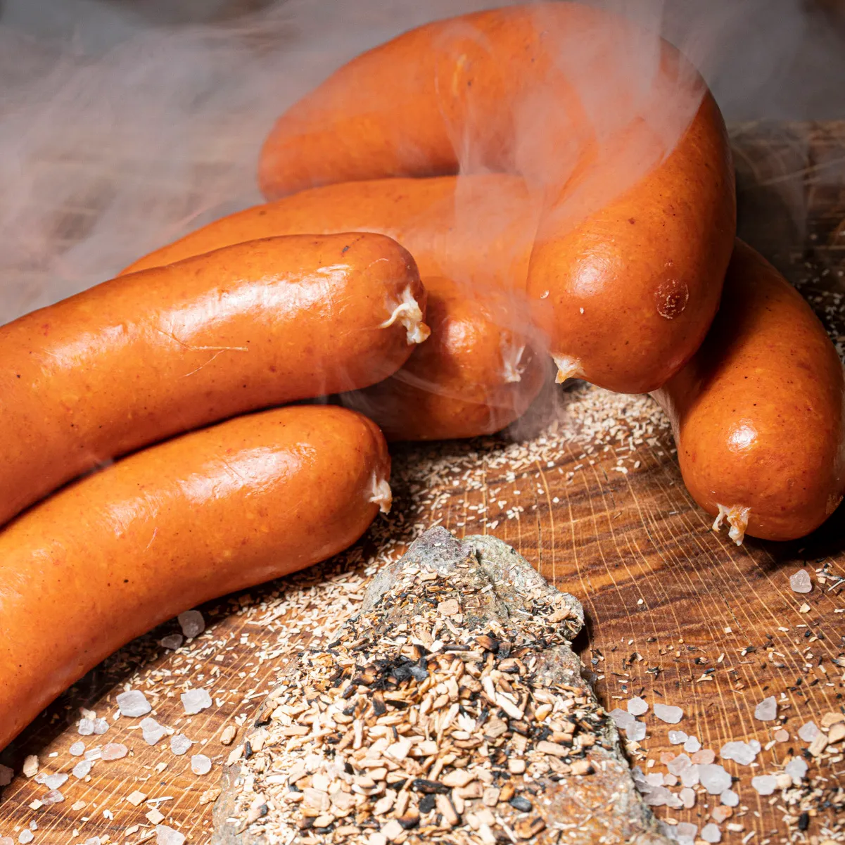 Ungarische Rauchwurst nach original ungarischem Rezept im Rauch und Holzspähnen auf Holzbrett.