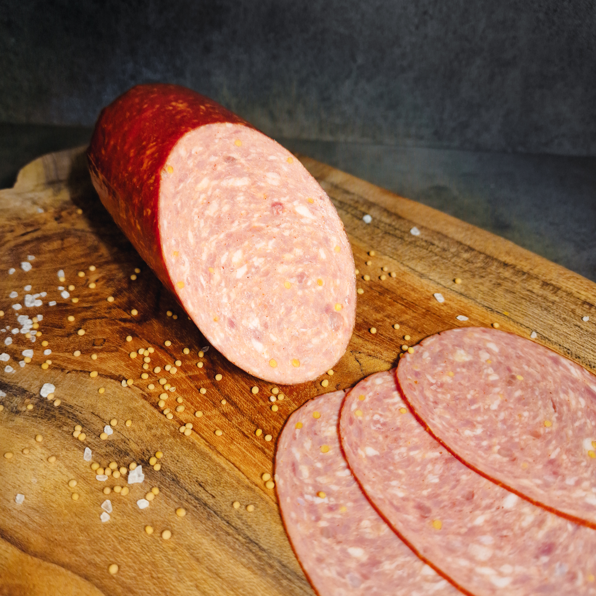 Kochsalami online bestellen. Kochsalami aufgeschnitten auf einem Holzbrett.