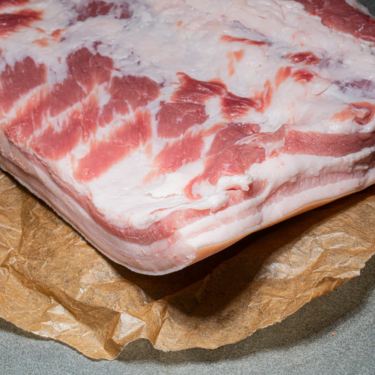 Eine ganze Seite Schweinebauch ohne Knochen auf Fleischpapier.