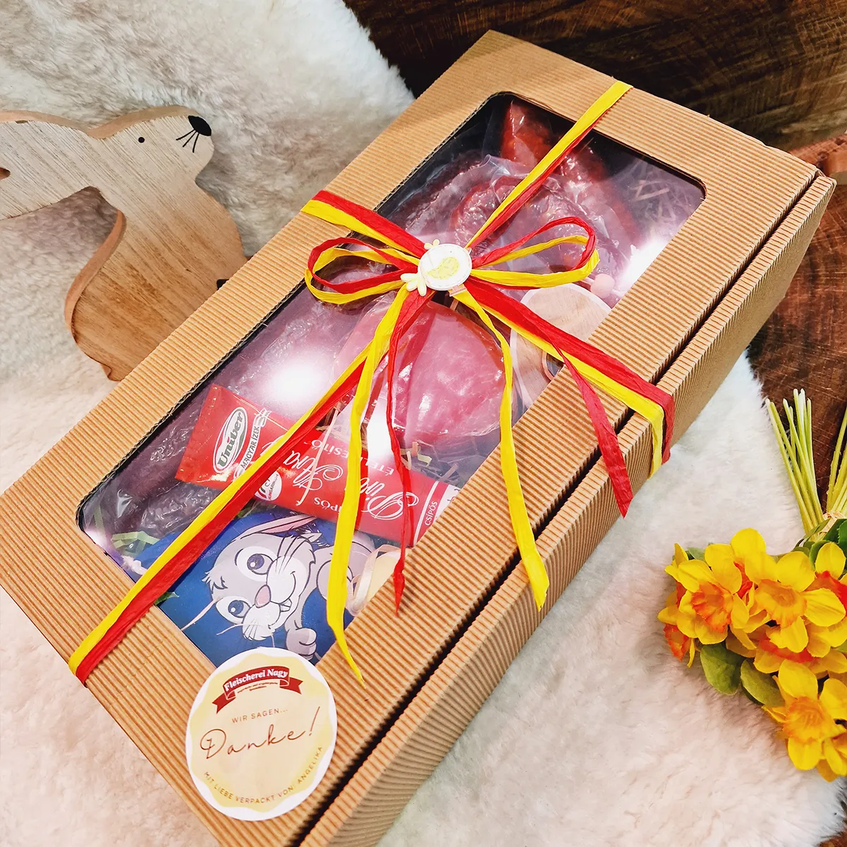 Ostergeschenk eingepackt mit Schleife und Feinkost wie ungarischer Wurst und Gulaschcreme als Inhalt.