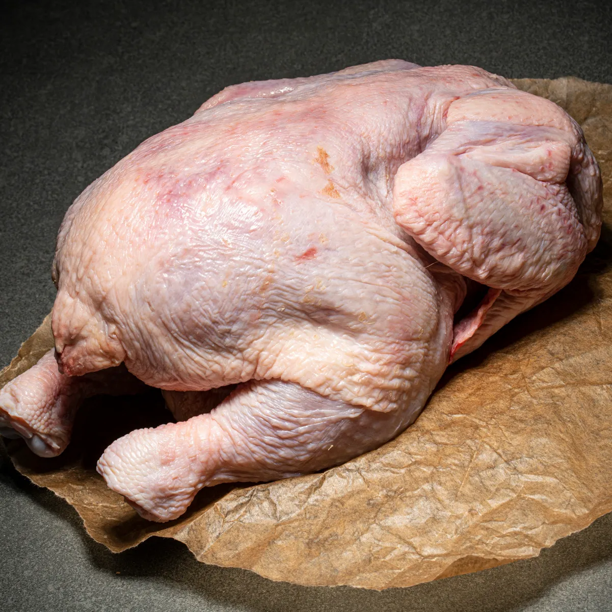 Ein ganzes Hühnchen auf Fleischpapier.
