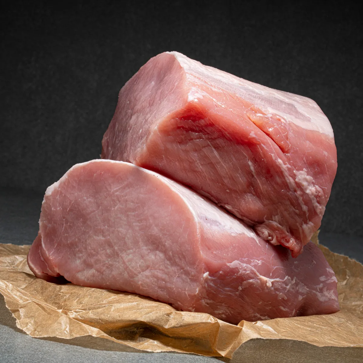 Schaelbraten vom Schwein zwei große Stücke liegen übereinander auf einem Fleischpapier.