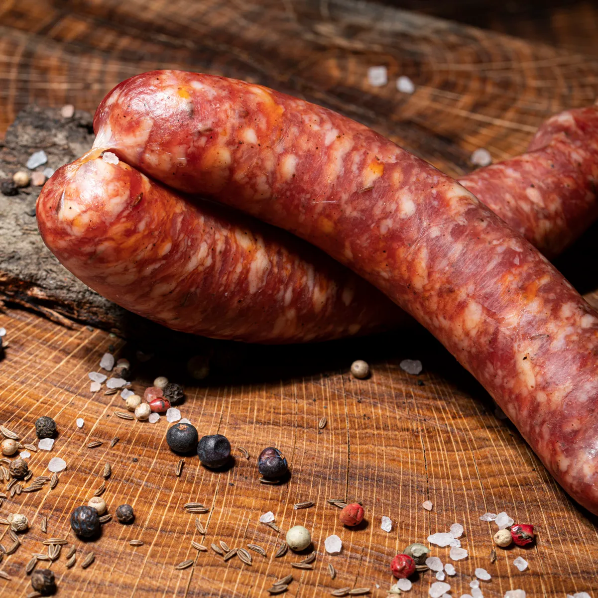 Unsere Kümmelknacker als idealer Snack für Zwischendurch! Zwei Kümmelknacker mit Salz-Pfeffer-Deko auf einem Holztisch.