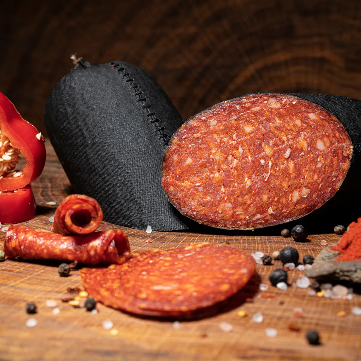 Entdecken Sie unsere leckere Paprikasalami! Kleine Paprikasalami aufgeschnitten auf einem Holzbrett.