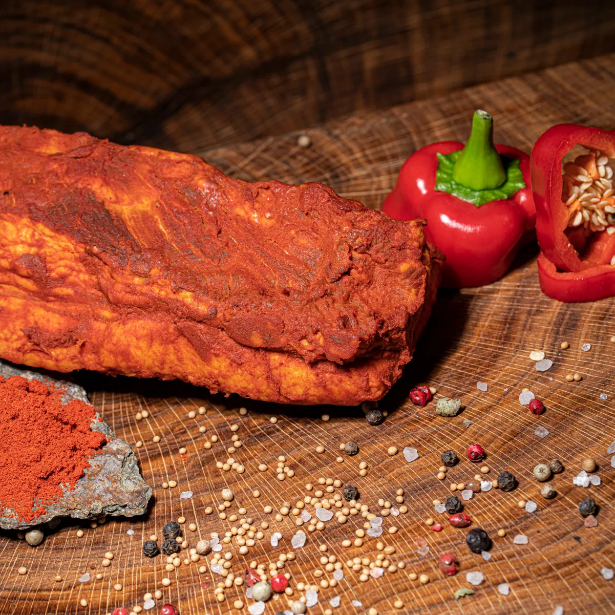 Geräucherter Paprikaspeck mit Paprikapulver Online bestellen. Geräucherter Paprikaspeck mit Paprikapulverdeko auf Holzbrett.