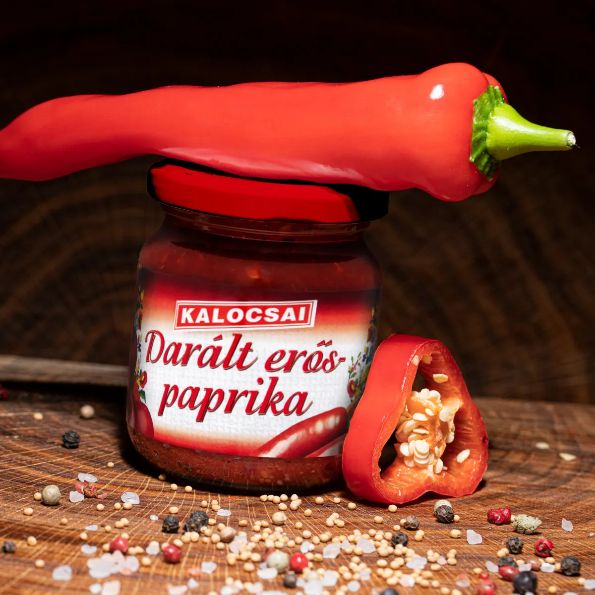 Kalocsai ungarisches Paprikapuerree scharf online kaufen. Kalocsai ungarisches Paprikapuerree scharf im Glas mit Deko auf Holzbrett.