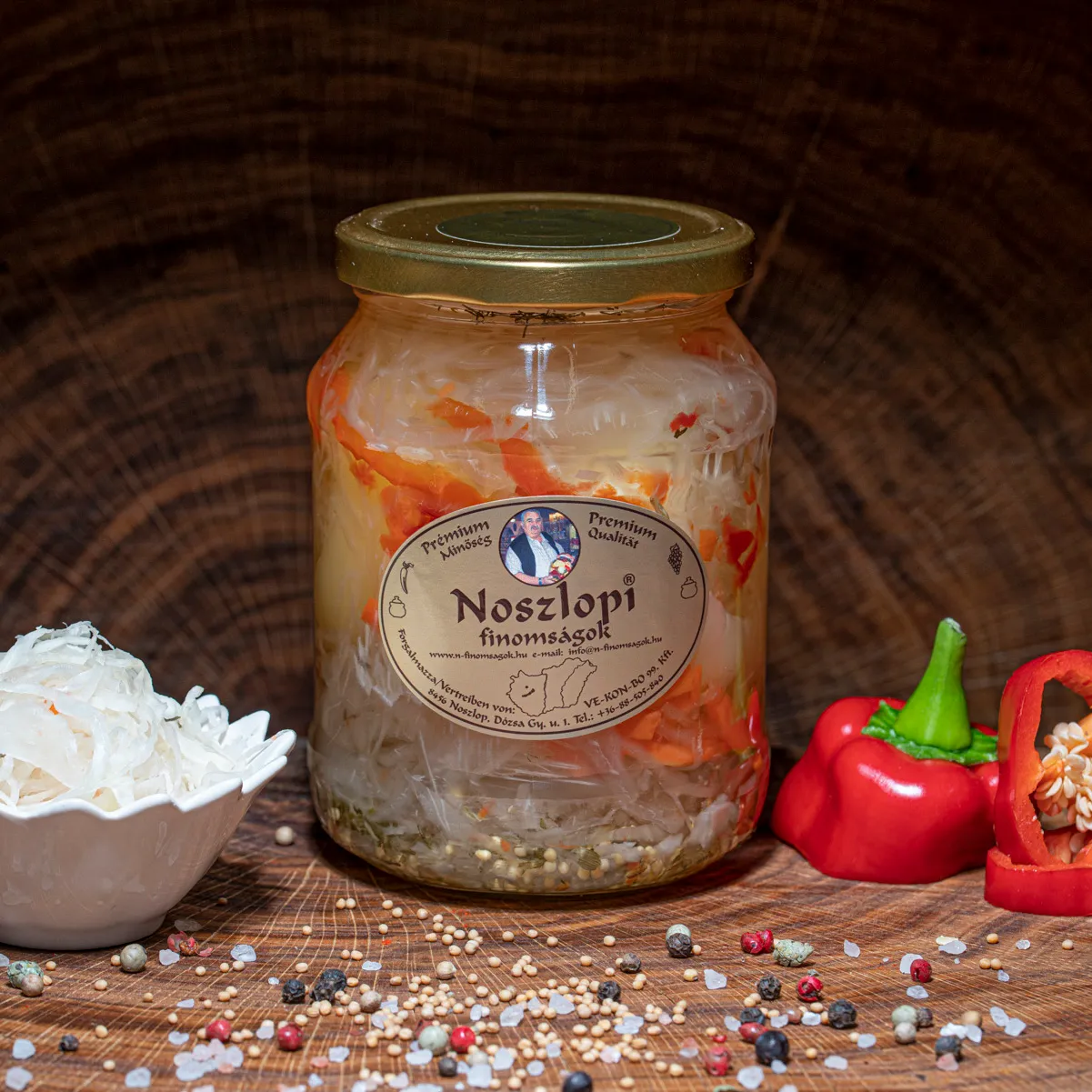 Noszlopi ungarisches, mildes Apfelpaprika mit Kraut im Glas jetzt ausprobieren! Noszlopi ungarisches, mildes Apfelpaprika mit Kraut im Glas auf Holzbrett.