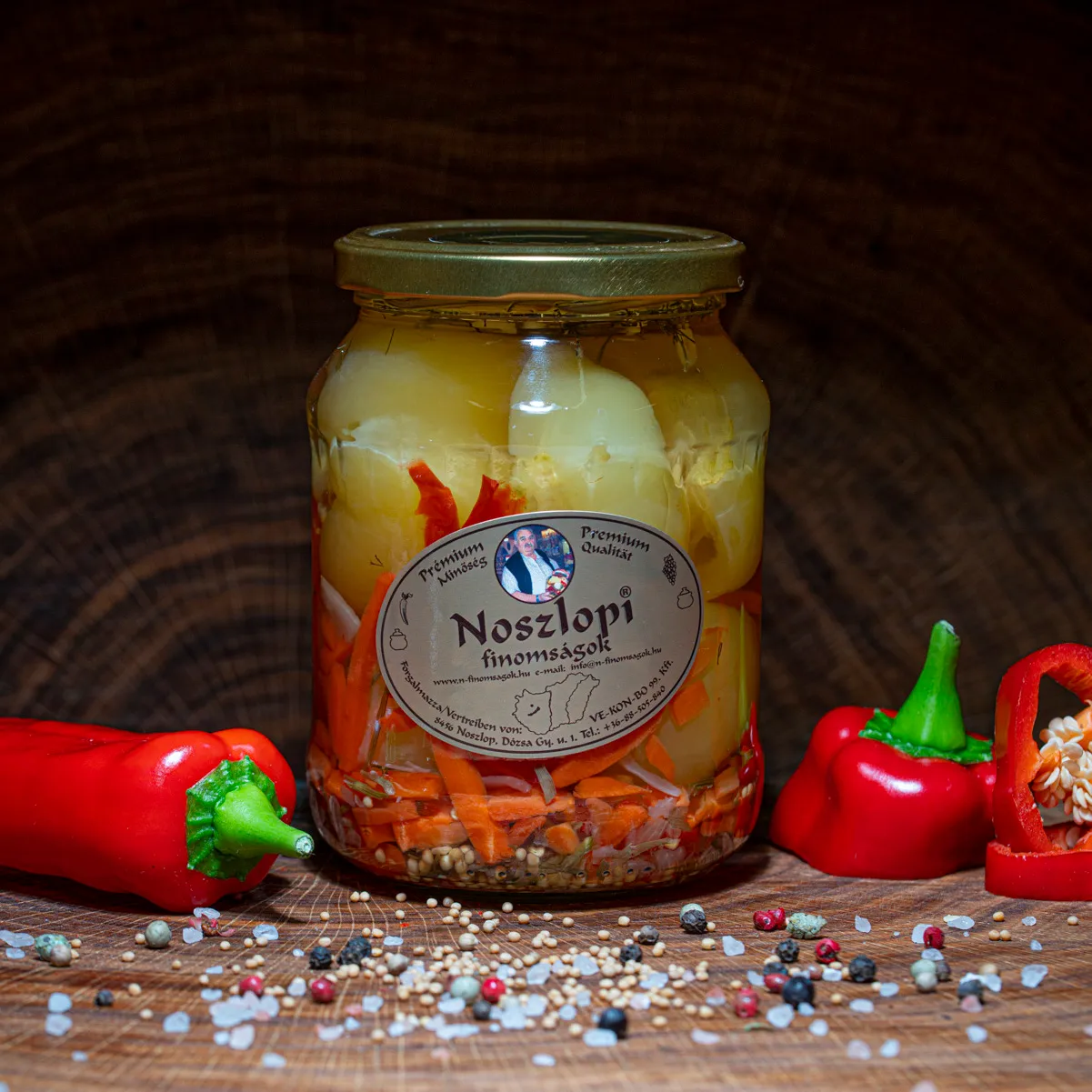 Noszlopi ungarisches Apfelpaprika in mild im Glas jetzt probieren. Noszlopi ungarisches Apfelpaprika in mild im Glas mit Paprika Deko auf Holzbrett.