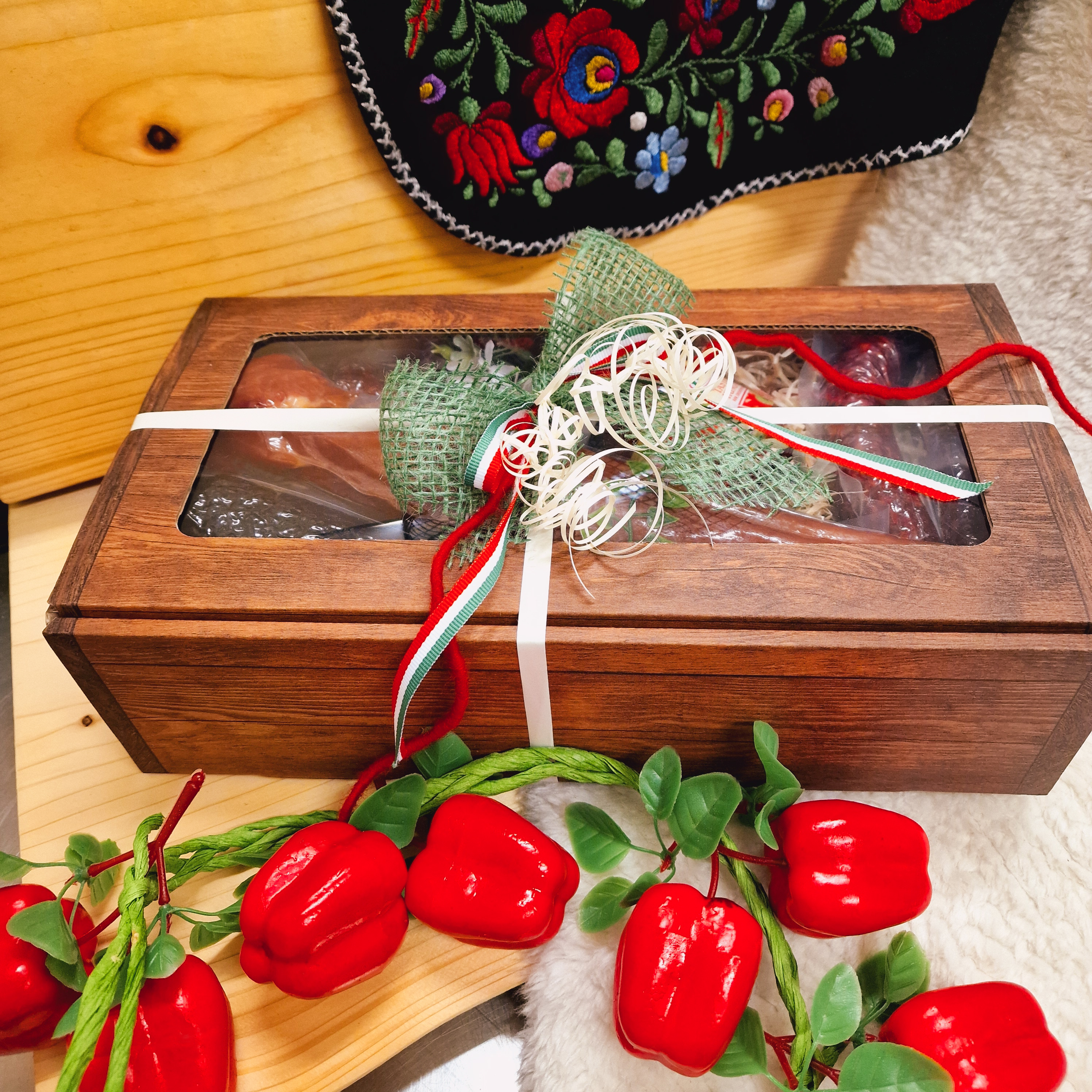 Geschenkbox geschlossen mit Deko und Schleife; mit Wurstwaren als Inhalt.