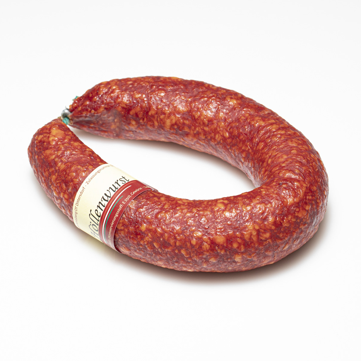 Scharfe Höllenwurst im Ganzen vor weißem Hintergrund.