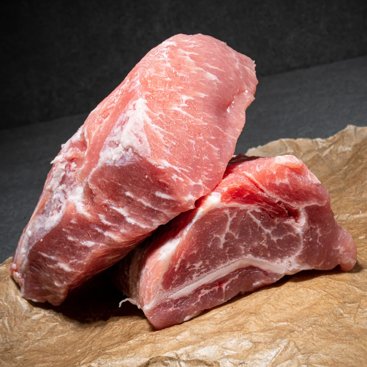 Mangalitza Schaelbraten zwei große Stücke übereinander gestapelt, auf Fleischpapier.